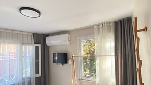 Une chambre d’hôtel avec un lit, un téléviseur fixé au mur, une fenêtre avec des rideaux et une balançoire en bois.