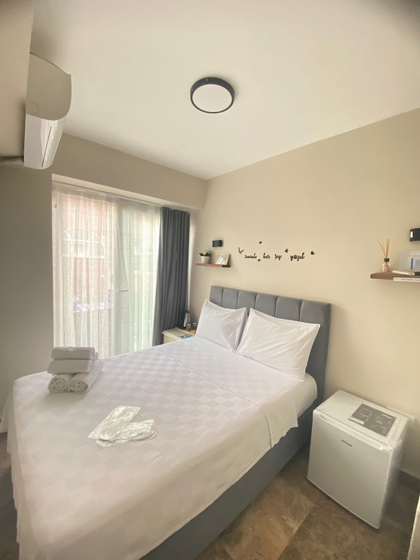 A neatly made bed with a checkered bedspread, a bedside table with a lamp, and a wall with a decorative phrase. - Buyukada Carsi Pansiyon (Adalar)