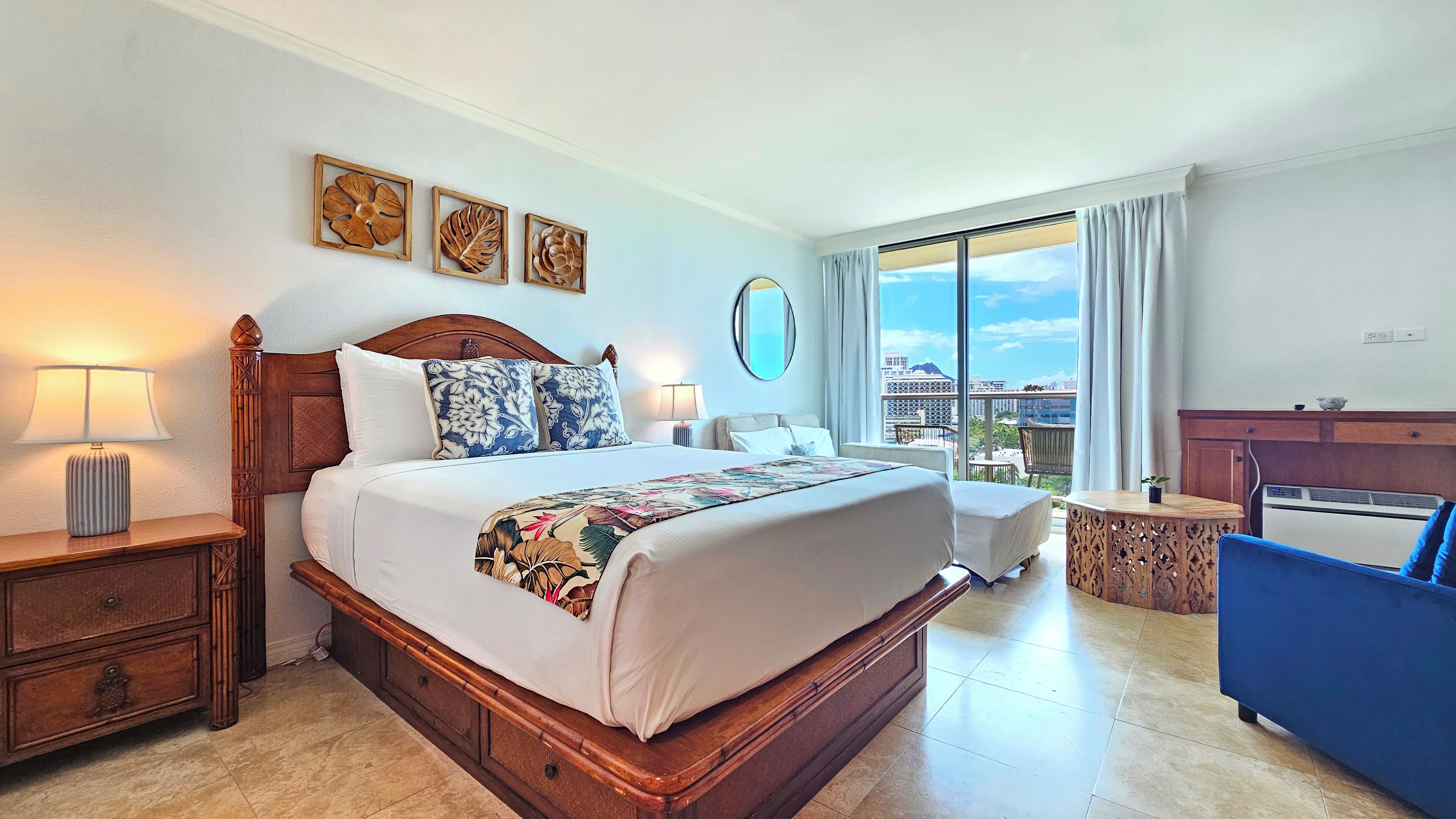 Une chambre d’hôtel avec un grand lit, un bureau, une chaise, un balcon avec vue et une grande fenêtre.