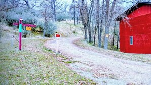 A red barn with a dirt path leading to it, surrounded by trees.