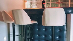 A bar area with two bar stools, a glass partition, and a bottle on the counter.