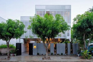A modern building with a glass facade, surrounded by trees and a paved courtyard. - Sila Prana Villa - Luxury Private Pool Villa Da Nang Beach (Da Nang)
