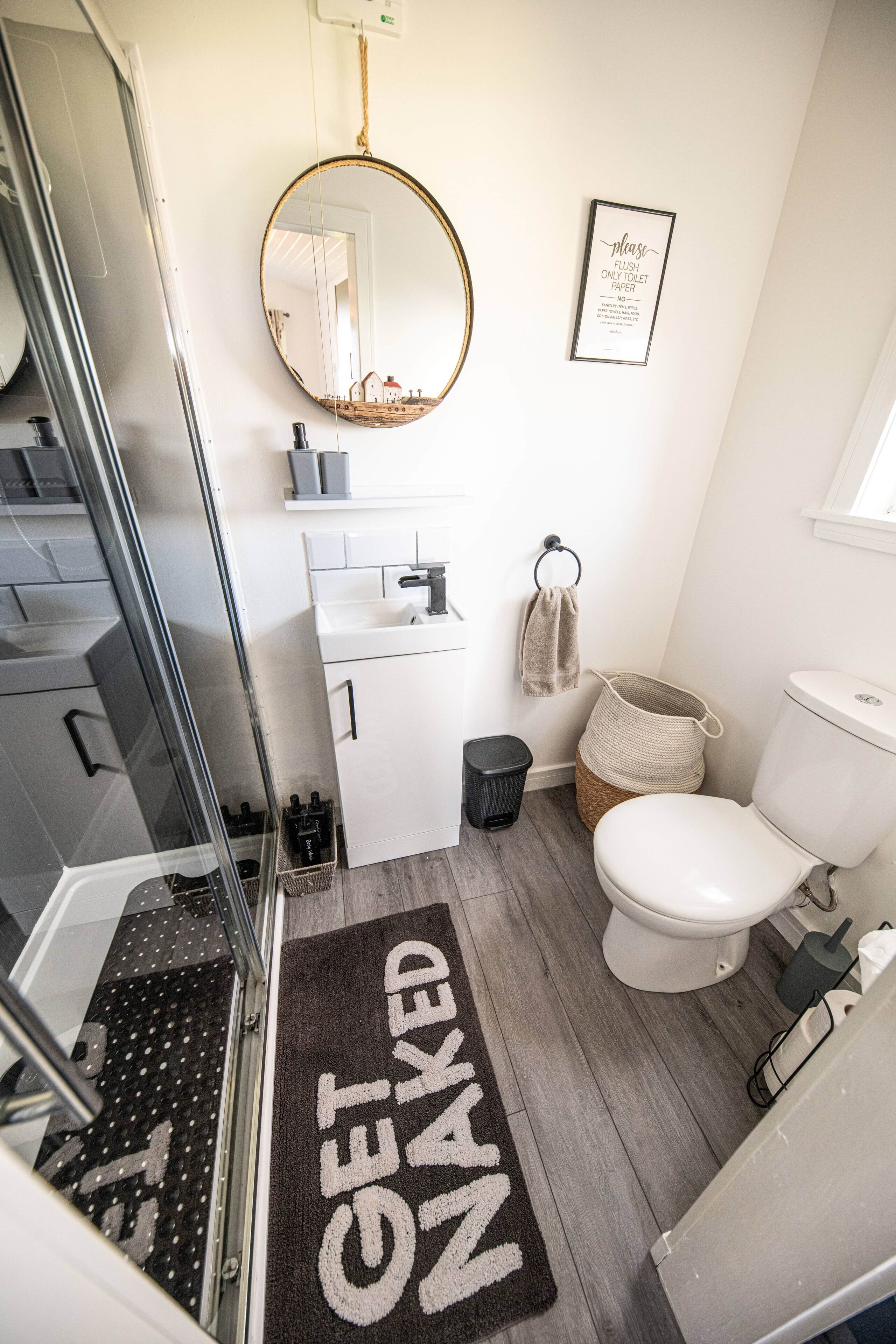 A bathroom with a shower, toilet, sink, and a mirror.