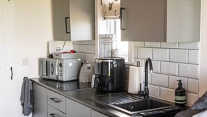Una cocina compacta con tostadora, cafetera y lavamanos.