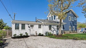 A two-story house with a gravel driveway and a tree in the front yard.