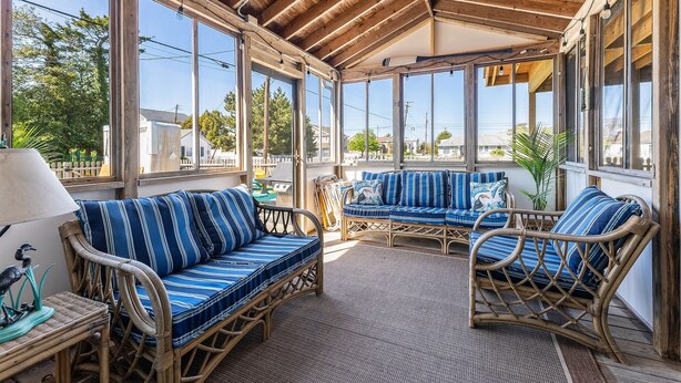A covered patio with wicker furniture and large windows.