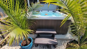 A hot tub surrounded by potted plants and a stone bench.