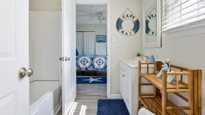 A bathroom with a bathtub, a shower, a sink, and a vanity. There is a circular wall decoration and a mirror above the vanity.