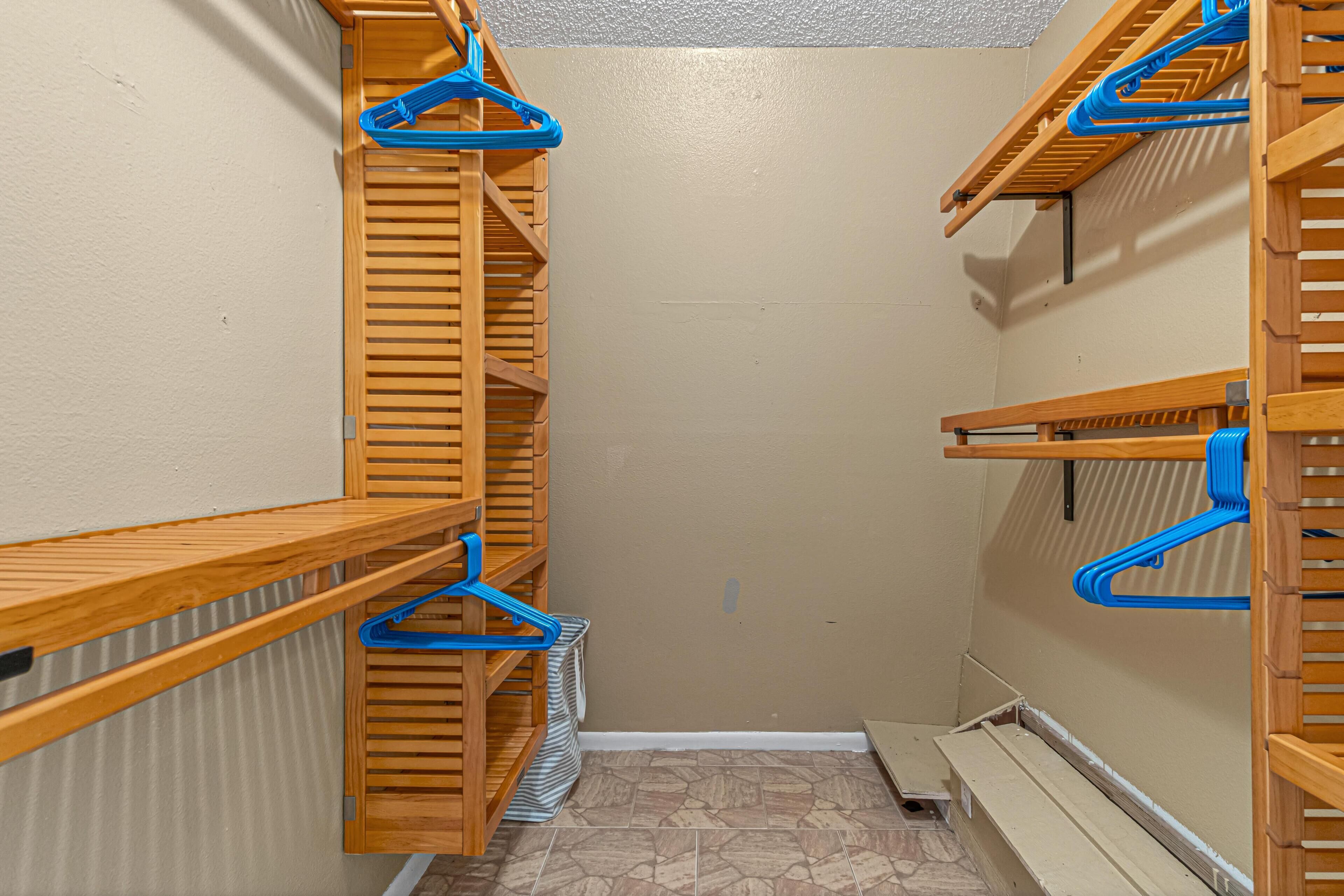 Un pasillo estrecho con estanterías de madera y perchas azules.