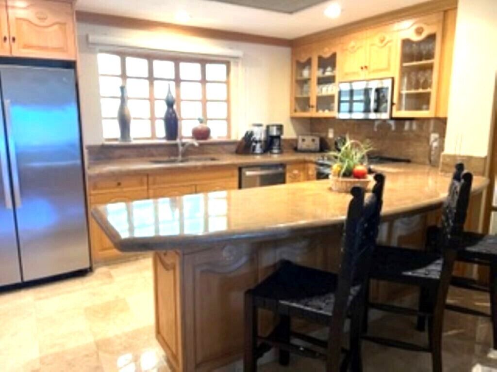 A kitchen with a central island, wooden cabinets, and a refrigerator.