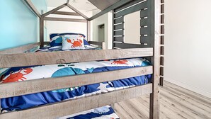 A bunk bed with a nautical theme, featuring a window with a view of the sky and a door with a handle.