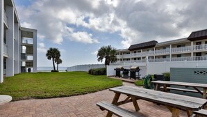 A courtyard with a brick patio, picnic tables, and a pool area with lounge chairs.
