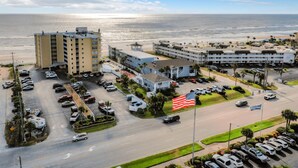 A hotel with multiple buildings, a parking lot, and a view of the ocean.