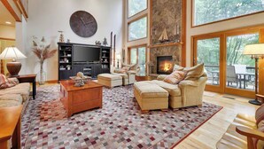 Ein geräumiges Wohnzimmer mit Kamin, großen Fenstern und hohen Decken.