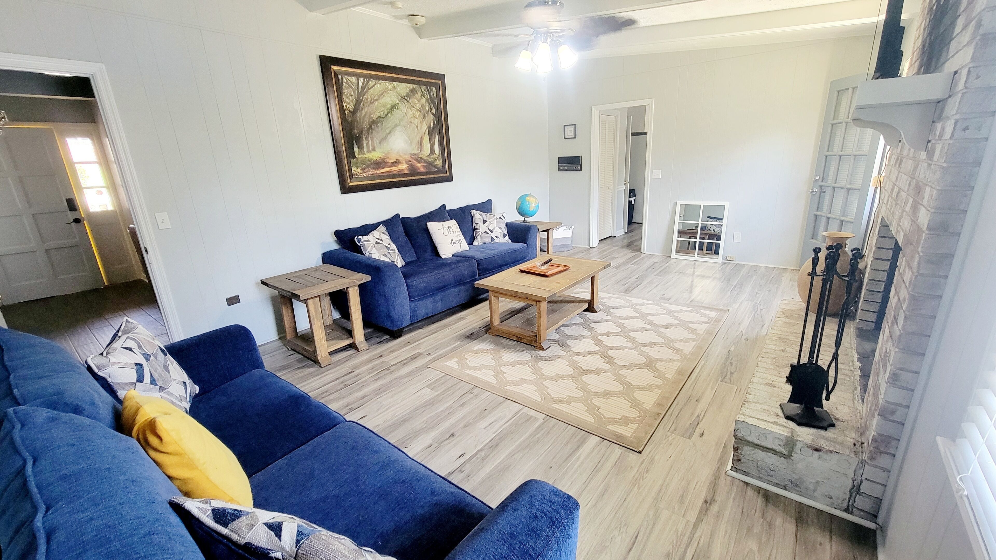 Ein Wohnzimmer mit einem blauen Sofa, einem Holztisch und einem gemusterten Teppich.