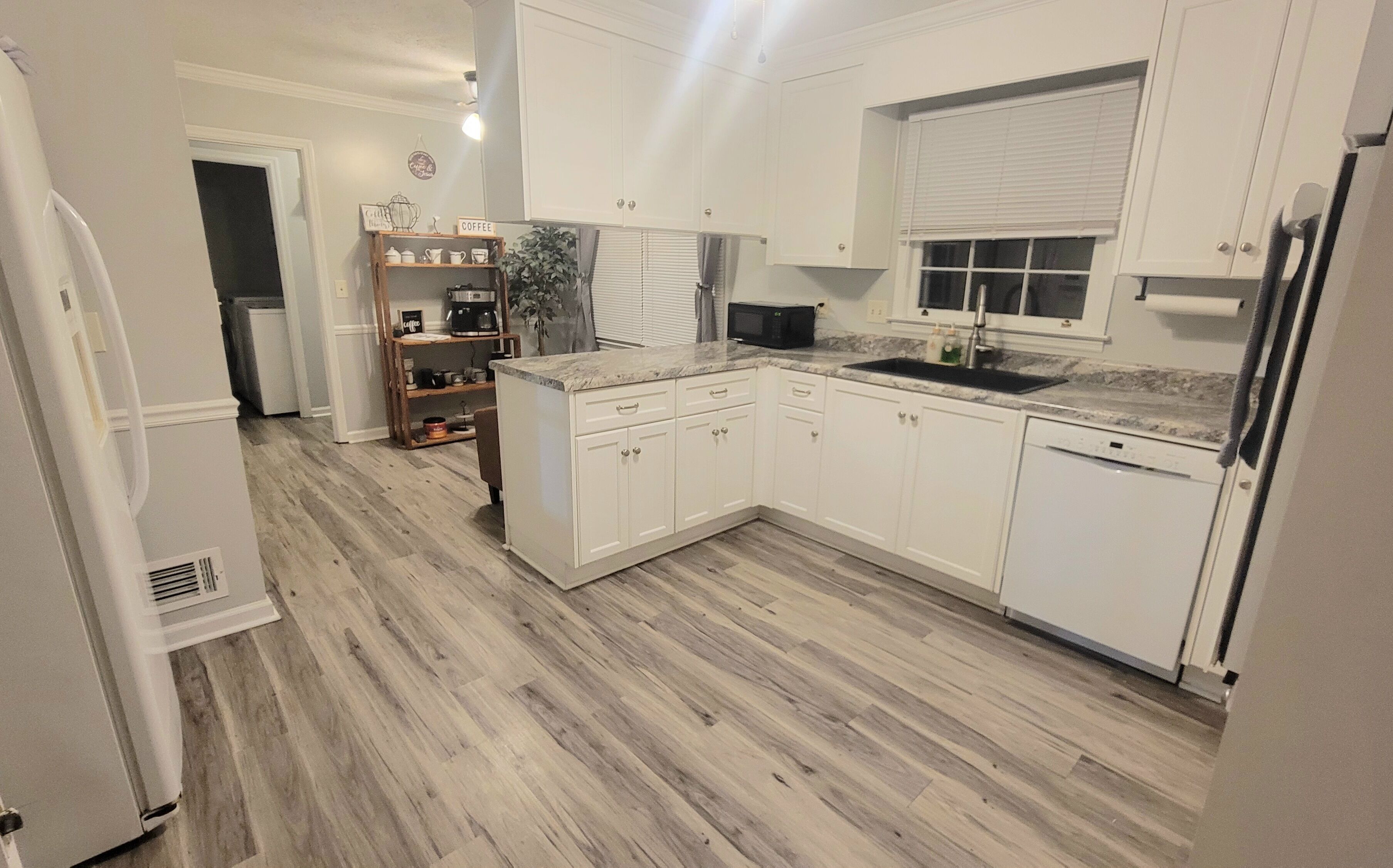 Een moderne keuken met witte kasten, een ingebouwde magnetron en een koffiehoek.