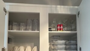 Una cocina con armarios blancos, una cafetera, un tostador y diversos utensilios de cocina.