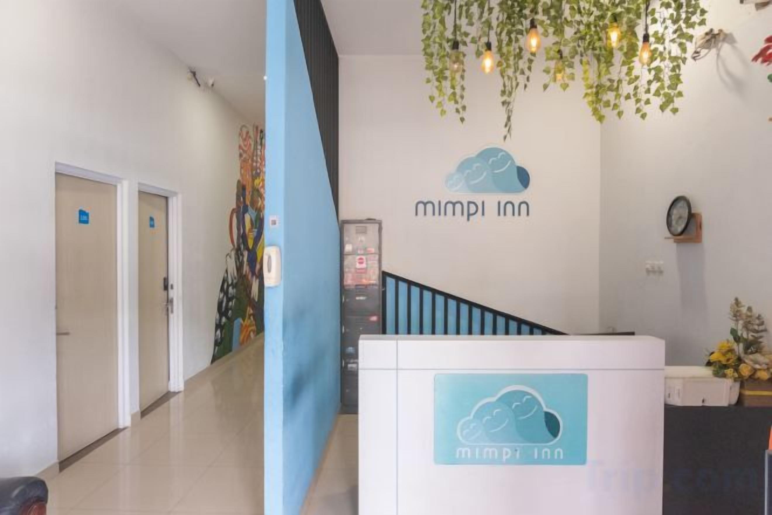Zona de recepción con una pared azul, un mostrador de recepción y una escalera.