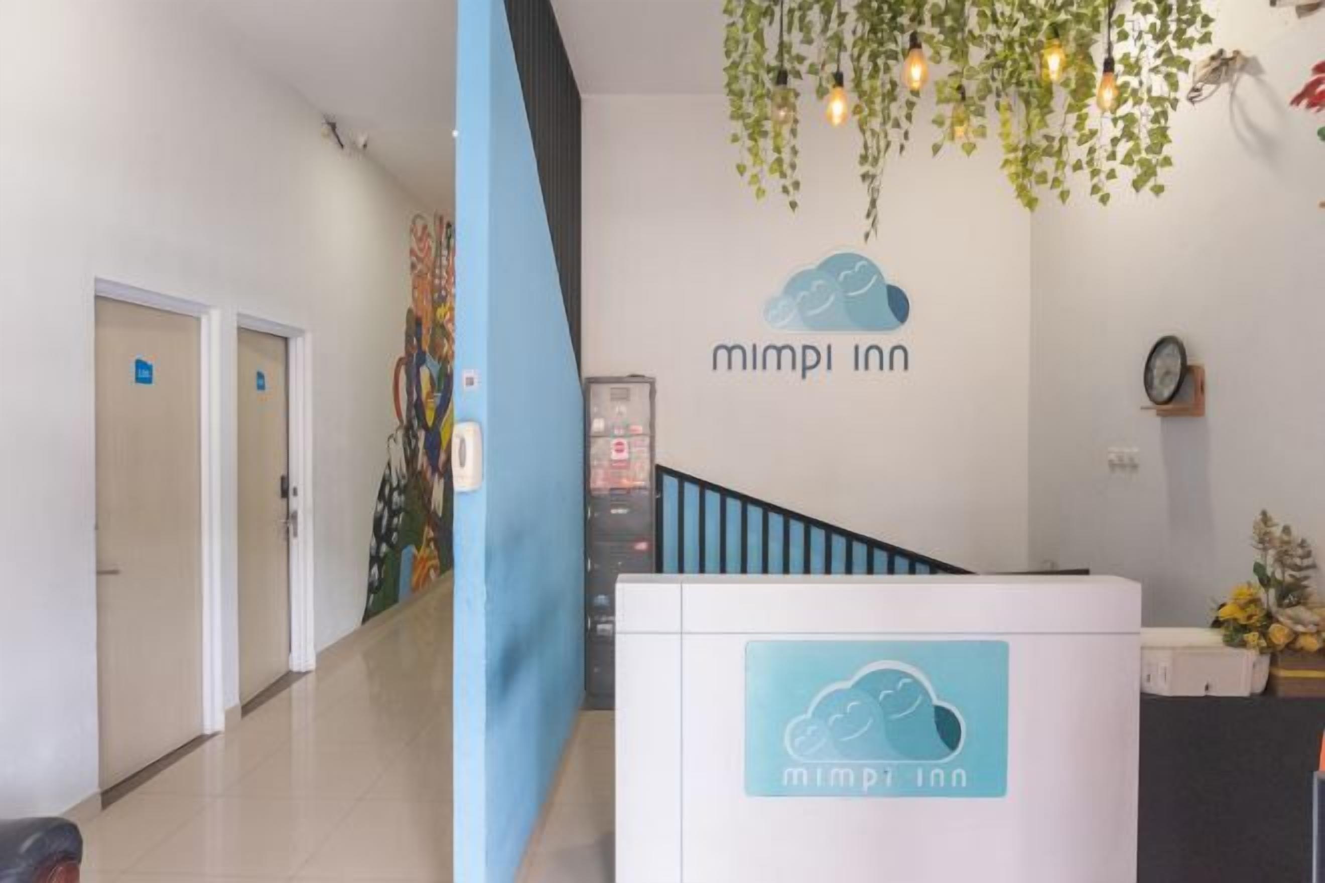 A reception area with a 'mimpi inn' sign, a staircase, and a wall-mounted clock.