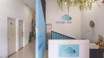 A reception area with a 'mimpi inn' sign, a staircase, and a wall-mounted clock.