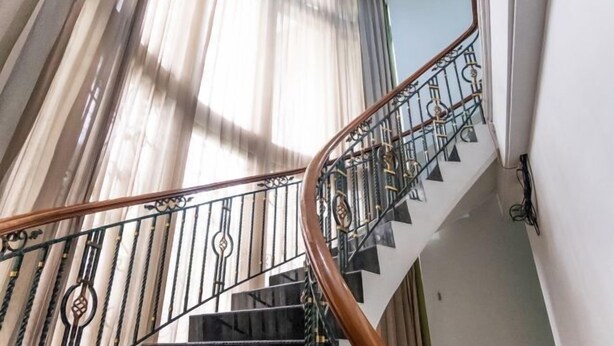 A staircase with black railings and wooden handrails. - INNCA Telaga Bodas, Semarang (Gajahmungkur)