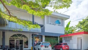 A modern building with a white facade, a large arched entrance, and a mural on the side. - INNCA Telaga Bodas, Semarang (Gajahmungkur)