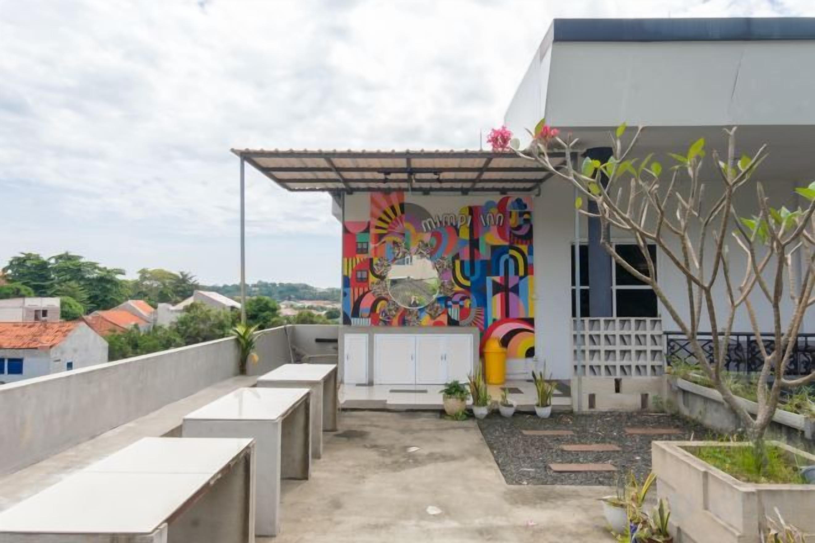 Una azotea con un mural colorido, un pequeño jardín y vistas de la ciudad.