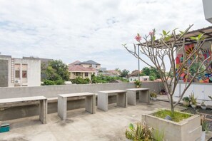 A rooftop terrace with concrete benches, potted plants, and a view of surrounding buildings. - INNCA Telaga Bodas, Semarang (Gajahmungkur)