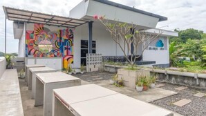 A modern building with a colorful mural, outdoor seating, and potted plants. - INNCA Telaga Bodas, Semarang (Gajahmungkur)