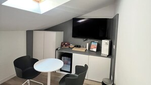A modern kitchen with a built-in TV, white cabinets, and a small dining area with two chairs and a table. - Lovoleti Lodge (Modena)