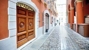 A narrow cobblestone street with a large wooden door on the left and a row of buildings on both sides. - Lovoleti Lodge (Modena)