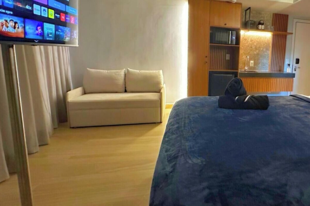 Ein Hotelzimmer mit Bett, einer Couch, einem Fernseher und einer Minibar.