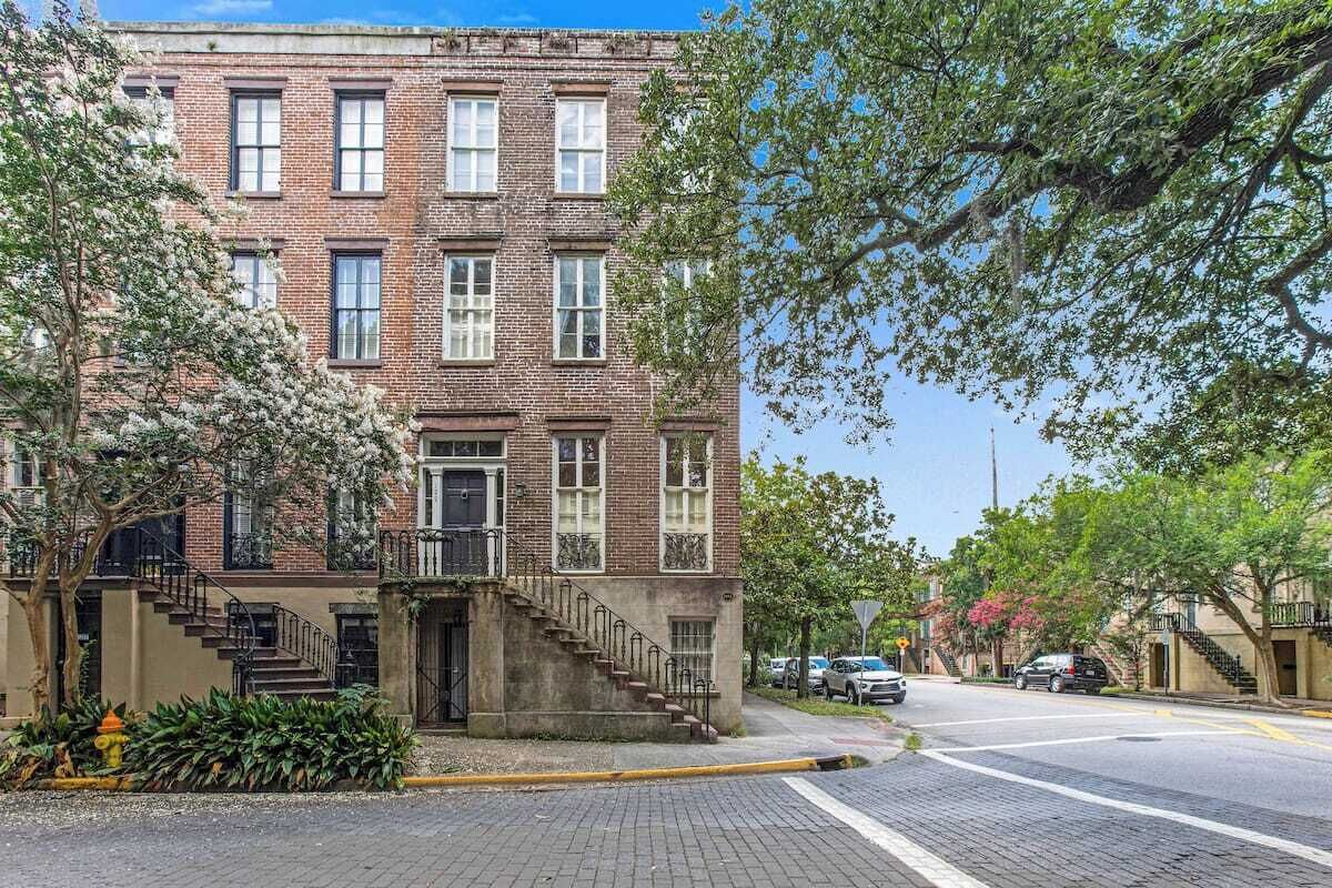 A multi-story brick building with a central staircase, a fire hydrant, and a sidewalk.