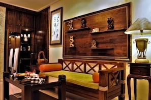 Una habitación tradicional japonesa con suelo de tatami, una mesa de madera baja, un banco acolchado y un armario de madera con objetos decorativos.