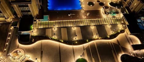 An aerial view of a hotel with a swimming pool, a Ferris wheel, and a landscaped area with circular planters.