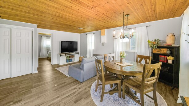 A spacious living room with a wooden ceiling, a dining table with chairs, a television, and a cozy sofa. - Summer Sale! Country Guesthouse near Waterparks and Birch Run Outlets (Bridgeport)