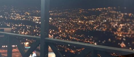 Panorama nocturno de una ciudad, visto desde una altura, probablemente desde un puente o torre.