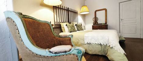 Un dormitorio con cama, una silla, dos lámparas, un espejo y una puerta.
