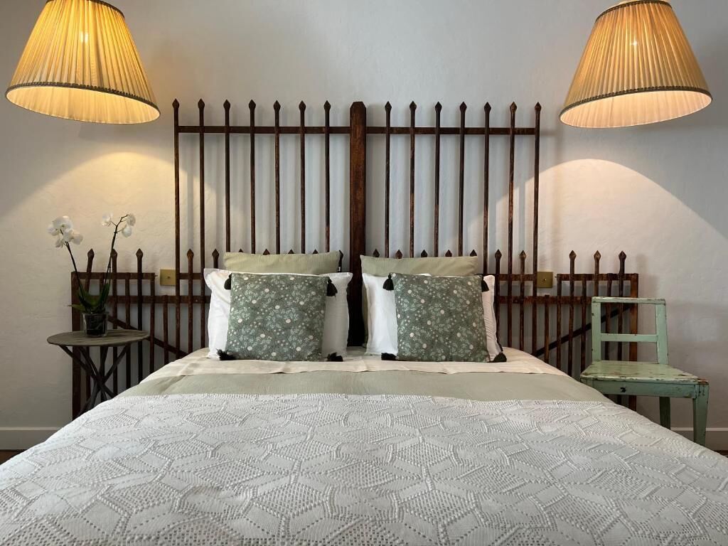 Un lit bien fait, recouvert d’une couvre-lit à motifs, avec deux lampes de chaque côté et une tête de lit décorative.