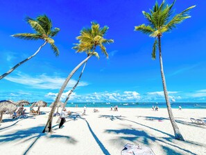 On the beach, white sand, sun-loungers, beach umbrellas