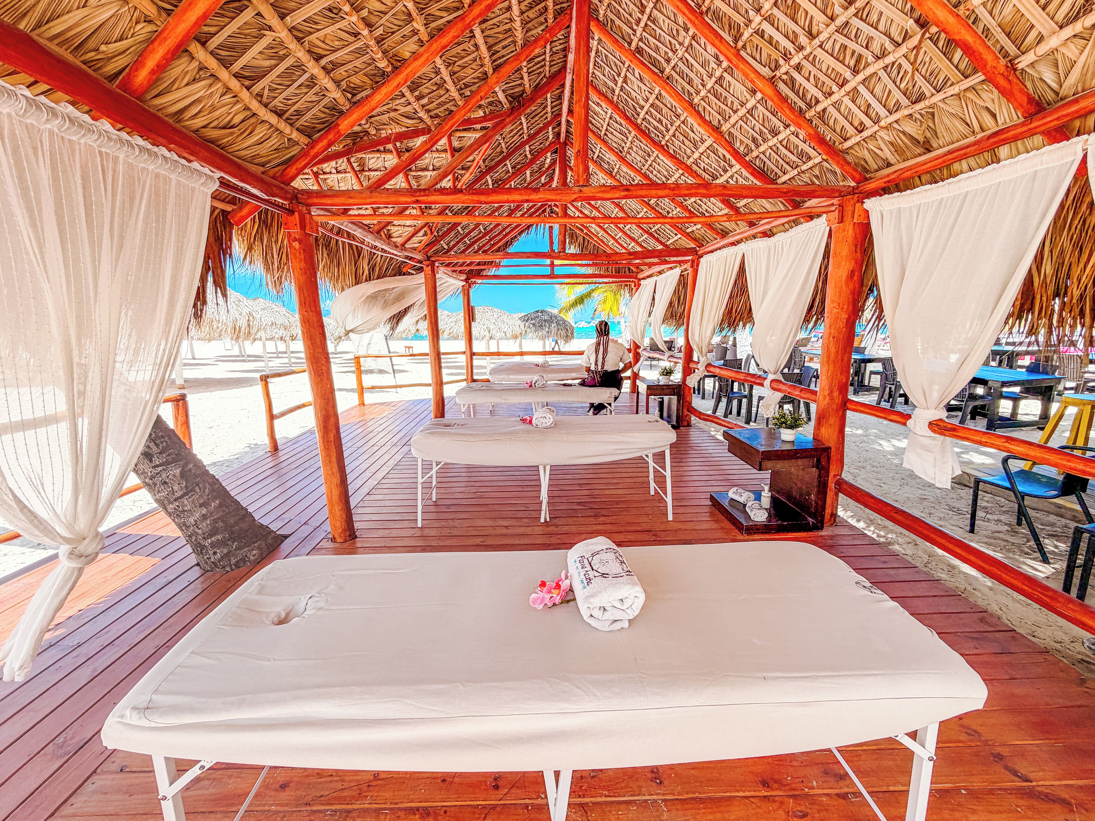 Una cabaña frente al mar con terraza de madera, una mesa de masaje y vistas al océano.