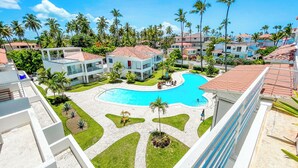 Um resort com piscina, palmeiras e edifícios modernos.