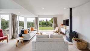 A modern living room with a sofa, armchairs, a TV, and a fireplace. - 7th Heaven (Napier)