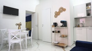 Een moderne, minimalistische woonruimte met een eethoek, een kitchenette en een zithoek.