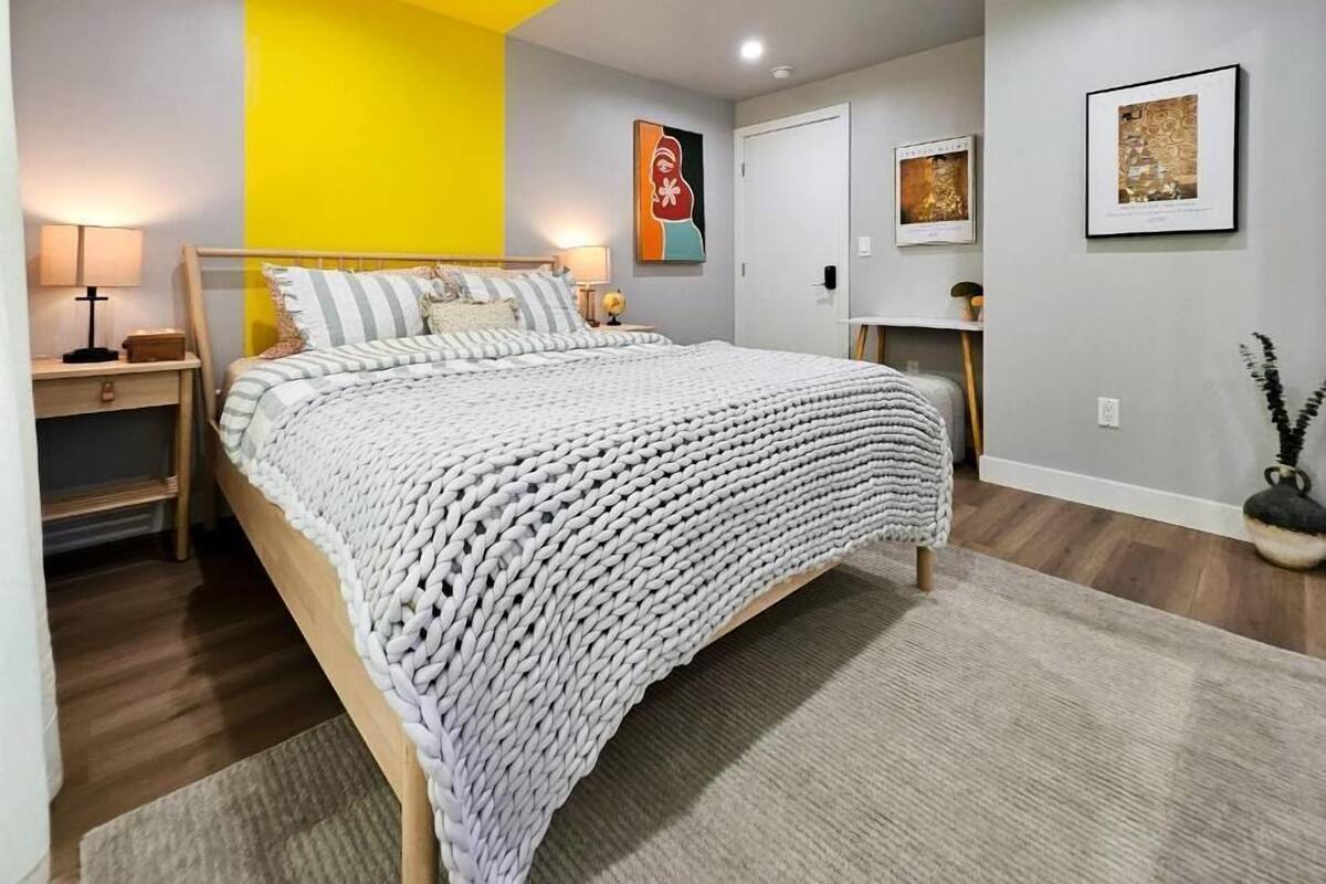 Un dormitorio con cama, mesitas de noche, una lámpara, un estante en la pared y un cuadro enmarcado.