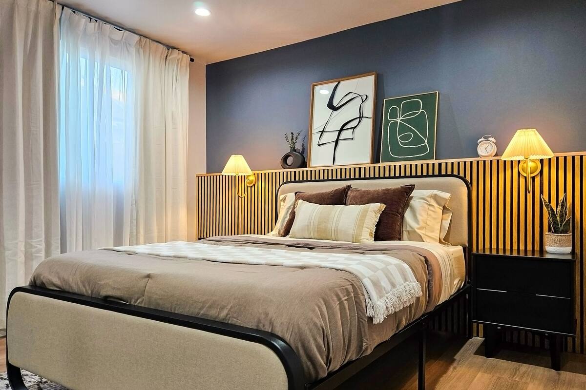 Un dormitorio moderno con cama, mesitas de noche y decoración en la pared.