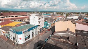 Une zone commerciale comprenant un magasin Suzuki, divers bâtiments aux couleurs vives et une vue dégagée sur le paysage environnant.