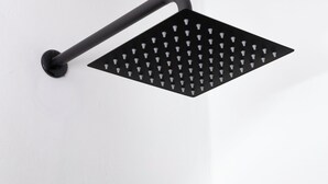 Une pomme de douche noire, dotée d’un manche incurvé, est fixée à un mur blanc.