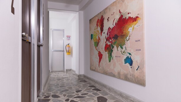 Un couloir avec un sol en pierre, un extincteur et une grande carte du monde accrochée au mur.