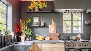 Una cocina moderna con estufa integrada, armarios de madera y ventana con vista a la vegetación.